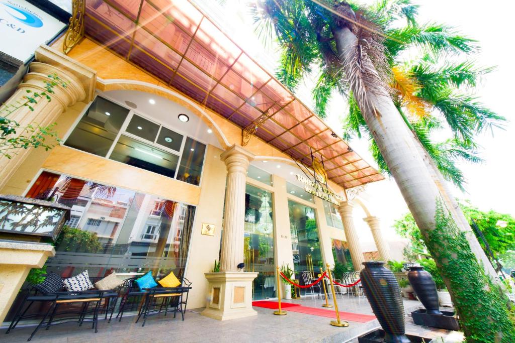 un edificio con sillas y palmeras delante de él en Sunshine Boutique Hotel Phu My Hung en Ho Chi Minh
