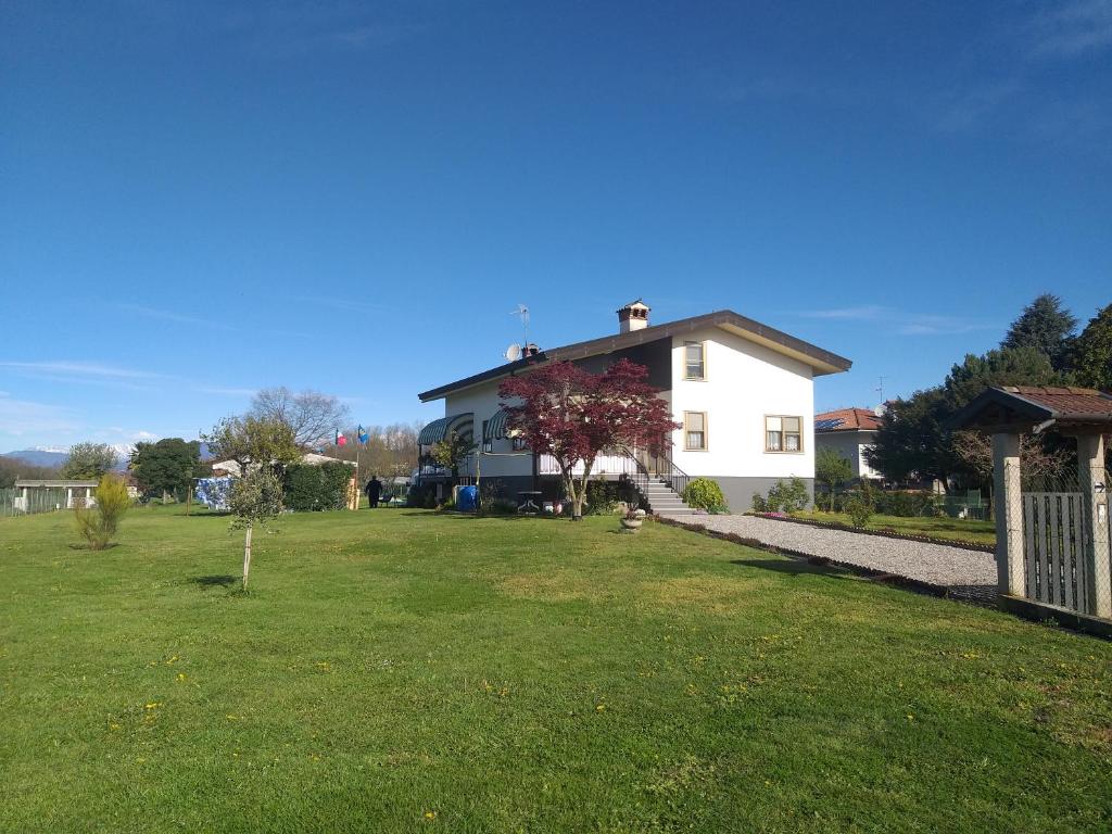 une maison blanche avec une cour agrémentée d'une pelouse verte dans l'établissement B&B DA ROBERTINO, à Tricesimo