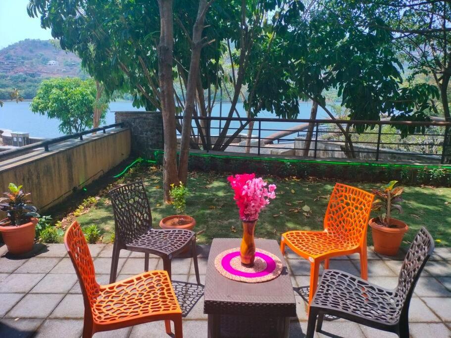 a table with four chairs and a vase with flowers on it at Portofino TreeHouse in Lavasa