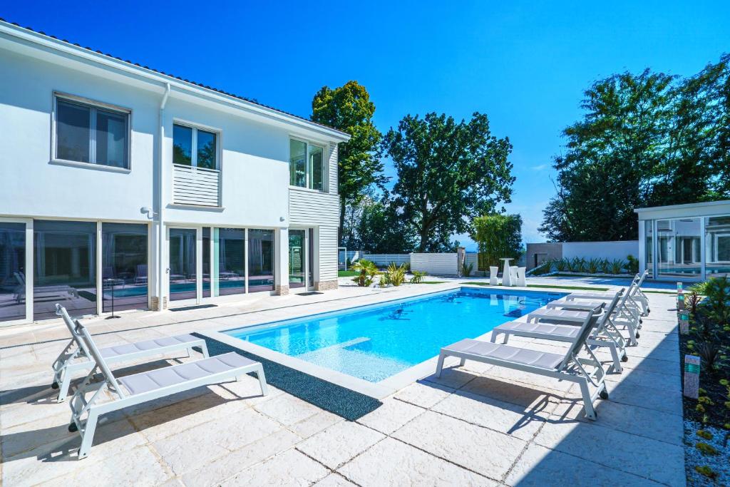 uma piscina com espreguiçadeiras e uma casa em VILLA VITTORIA B&B - Wellness em Terme di Miradolo