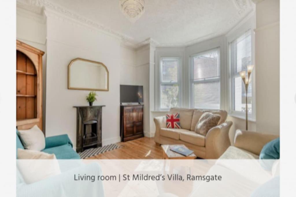 a living room with a couch and a fireplace at St Mildreds Villa, Ramsgate Royal Harbour, Kent in Ramsgate