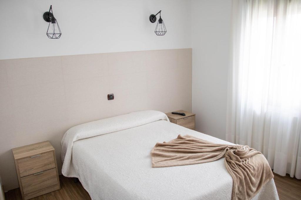 a white bedroom with a bed and a window at Hotel Maria del Mar in Noja