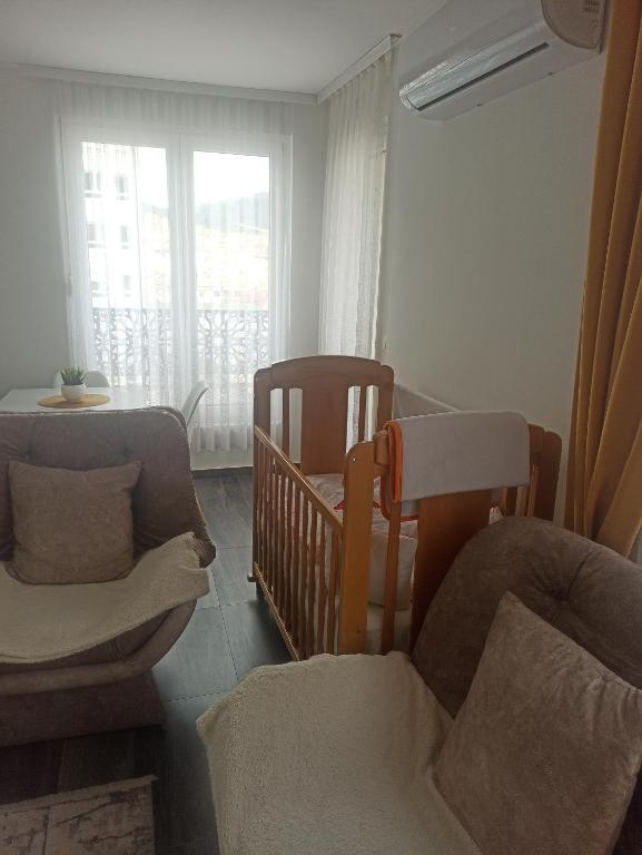 a living room with a crib and a chair at Elif Apartman in Novi Pazar