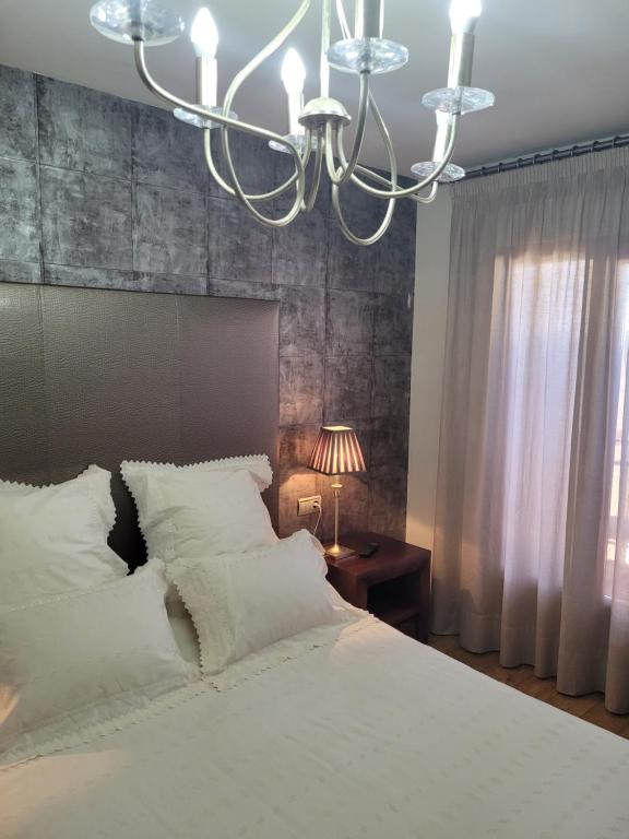 Un dormitorio con una gran cama blanca y una lámpara de araña. en Privada Confort Granada en Granada