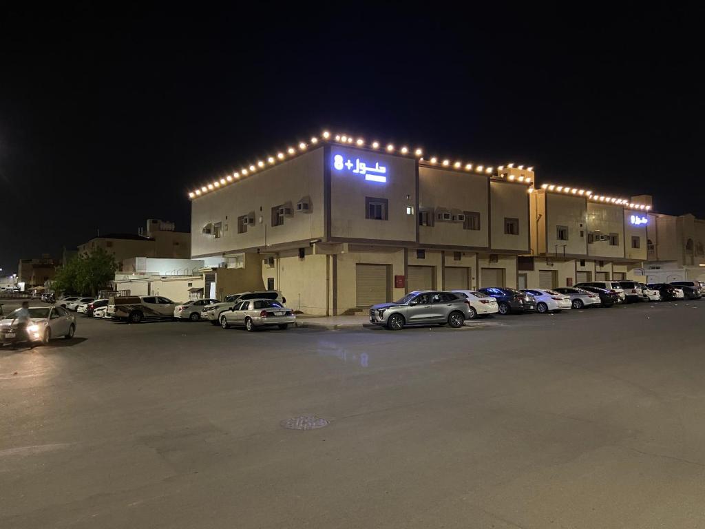 een gebouw met auto's geparkeerd op een parkeerplaats 's nachts bij حلول 9 in Abyār ‘Alī