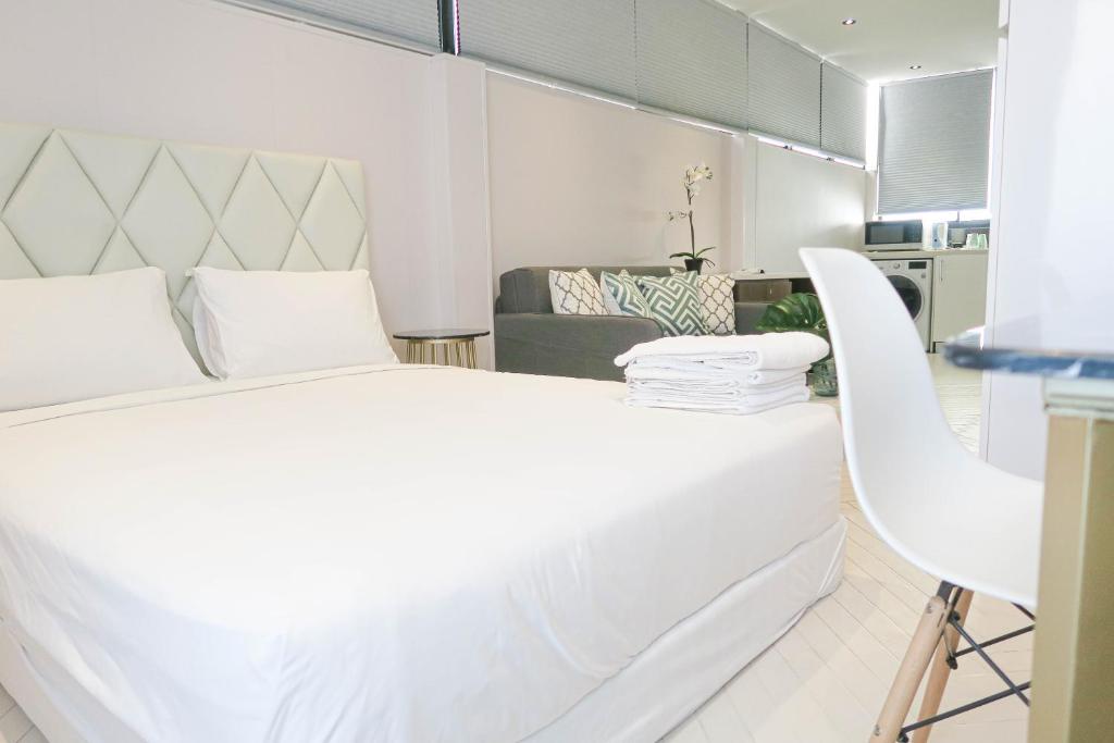 a white bedroom with a large bed and a chair at Comfy Studio 7 by ReCharge in Singapore