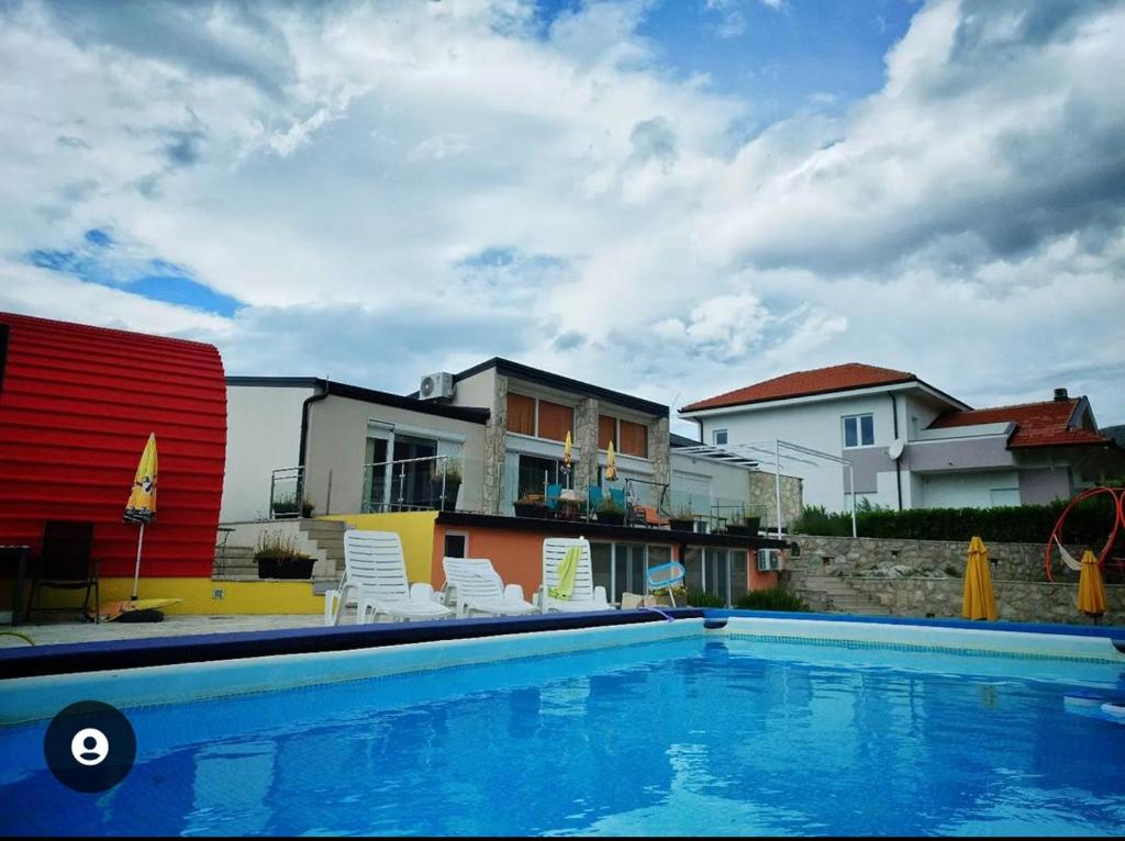 a swimming pool with chairs and houses in the background at Villa Lyra in Trebinje