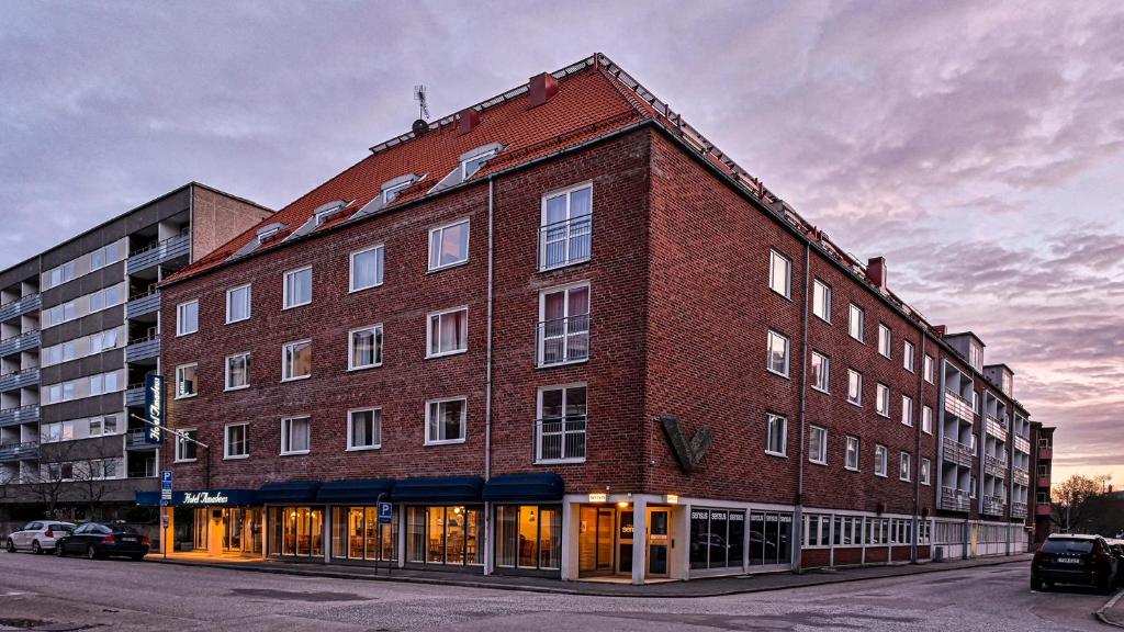 a large red brick building on a street at Hotel Amadeus in Halmstad