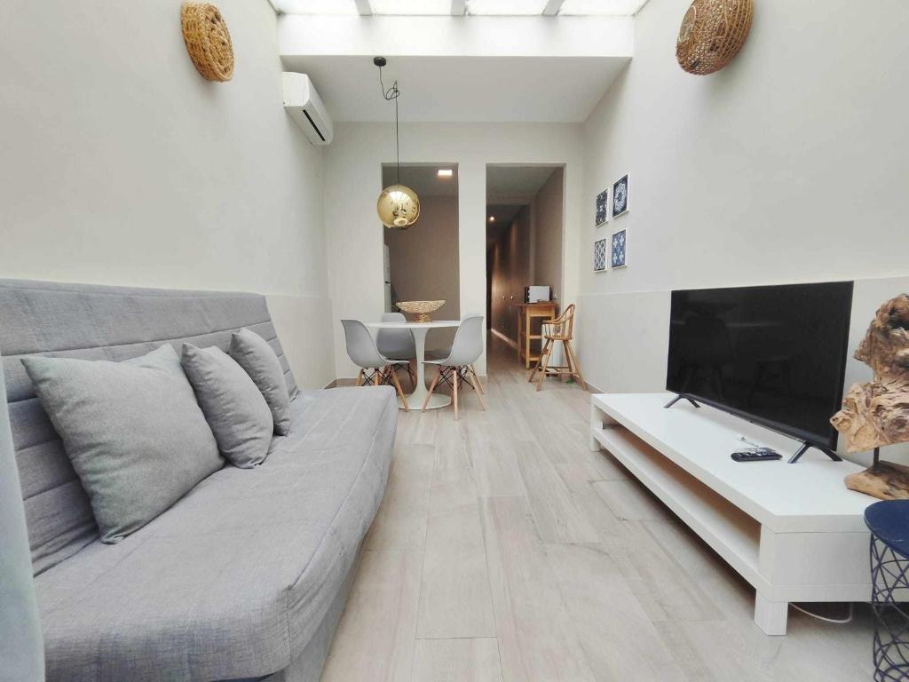 a living room with a couch and a flat screen tv at Mazi Apartments Chic in Badalona