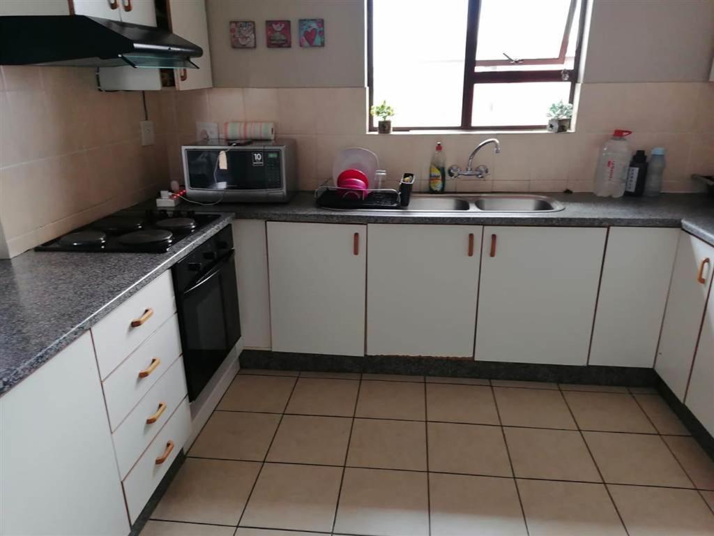 a kitchen with white cabinets and a sink and a microwave at 3The Olive Complex Richards Bay 3900 in Richards Bay
