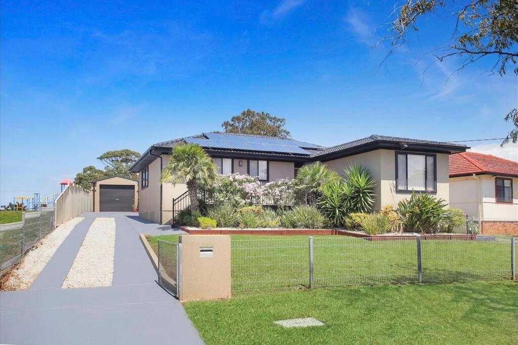 uma casa grande com um portão e uma entrada em Sunny Shores House with Private Pool em Lake Illawarra