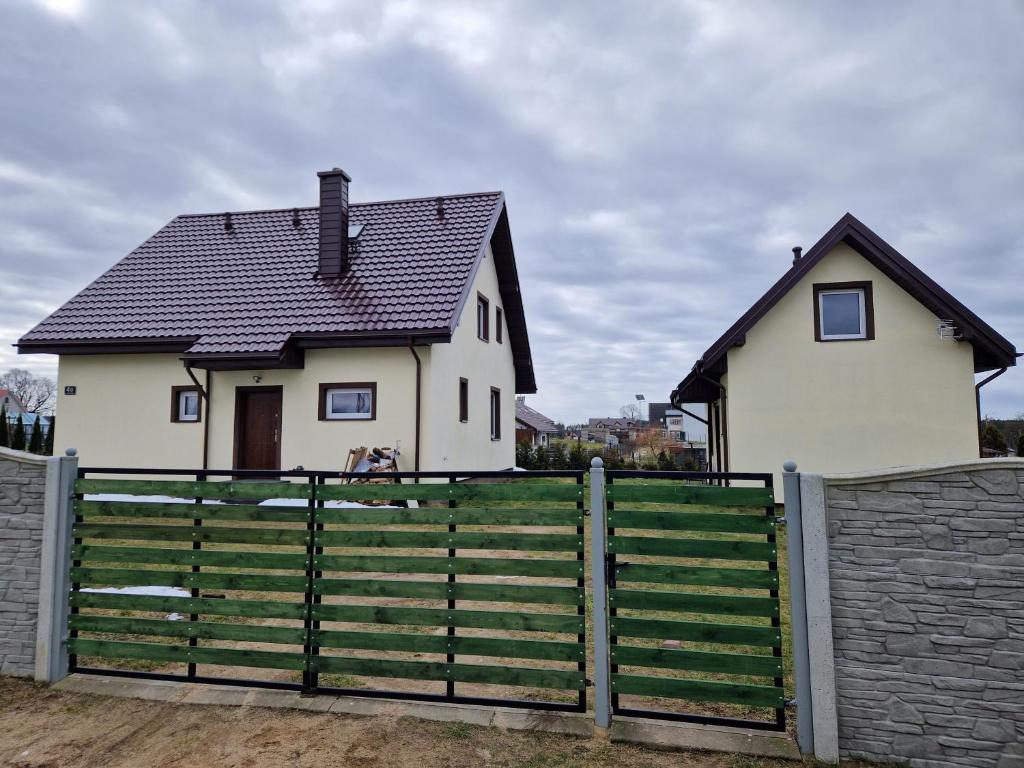 Biały dom z czarnym dachem za płotem w obiekcie Domki na Kaszubach w mieście Bukowina
