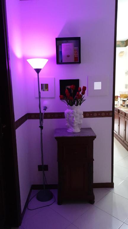a purple room with a lamp and a vase of flowers at Alba central City in Palermo