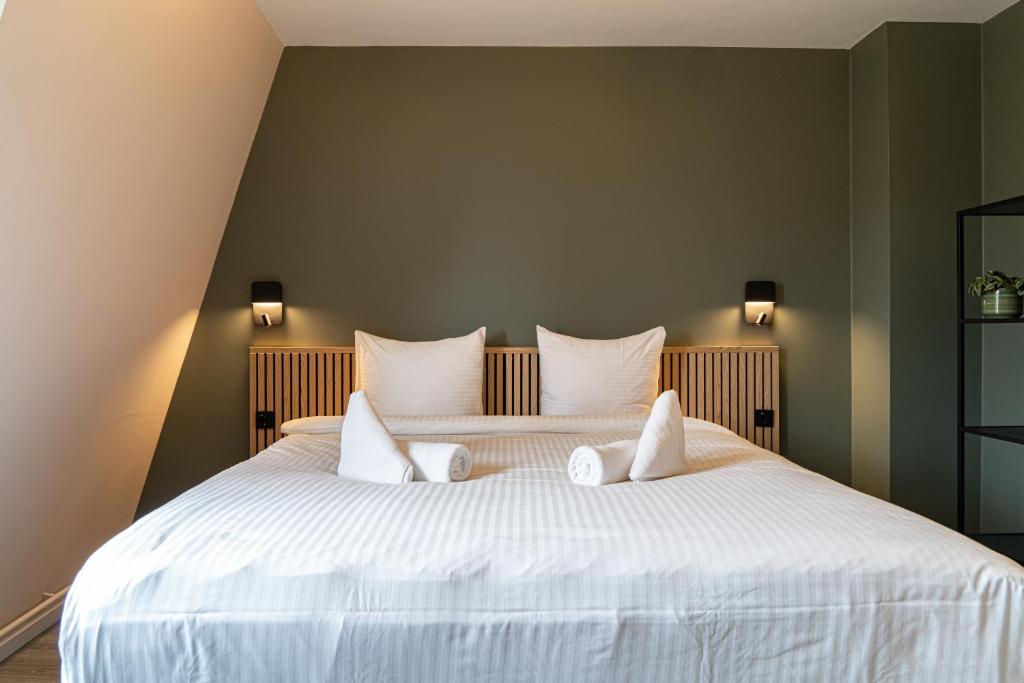 a bedroom with a large white bed with three pillows at Hotel de Duif Lisse - Schiphol in Lisse