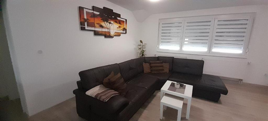 ein Wohnzimmer mit einem schwarzen Sofa und einem Tisch in der Unterkunft Apartman XXL in Brčko