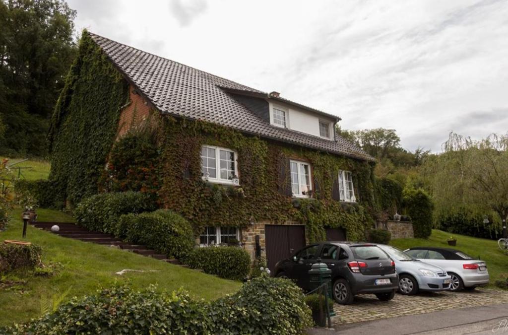 une maison couverte de lierre avec deux voitures garées devant dans l'établissement Chez Huguette, à Profondeville