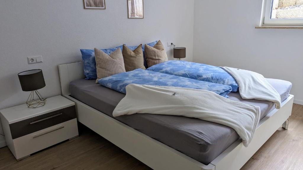 Una cama con sábanas azules y almohadas. en Moderne gemütliche Ferienwohnung in Friedrichshafen, en Friedrichshafen