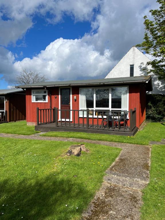 una casa roja y blanca con una mesa en el patio en Chalet 31 en Seaton
