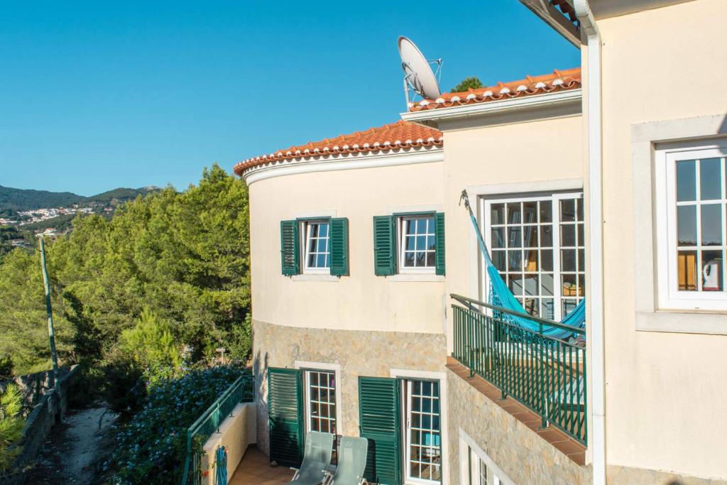 een gebouw met groene luiken en een balkon bij Amazigh Guincho Hostel & Suites in Cascais