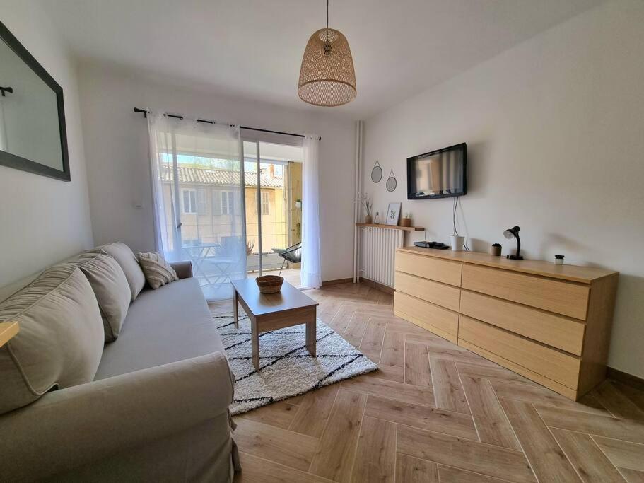 un salon avec un canapé, une télévision et une table dans l'établissement Les studios d'Aurélia - Grand Théâtre de Provence, à Aix-en-Provence