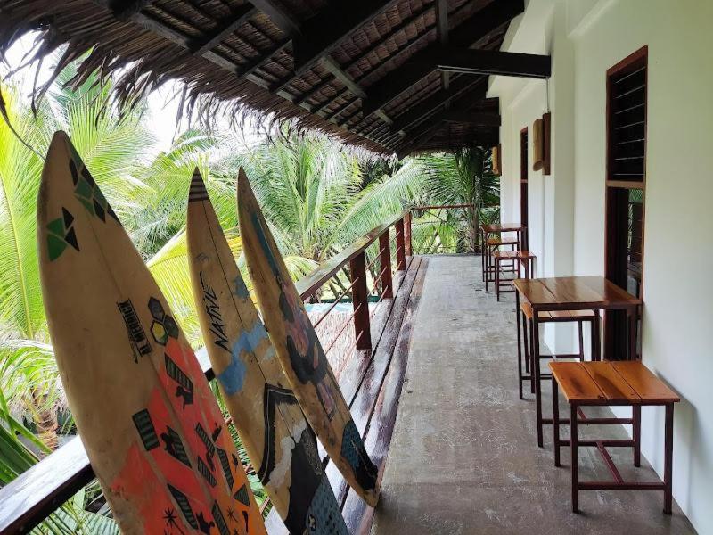 eine Reihe von Surfbrettern, die an ein Gebäude mit Tischen und Stühlen lehnen in der Unterkunft Lexias Hostel and Workspace - Siargao in Catagnan