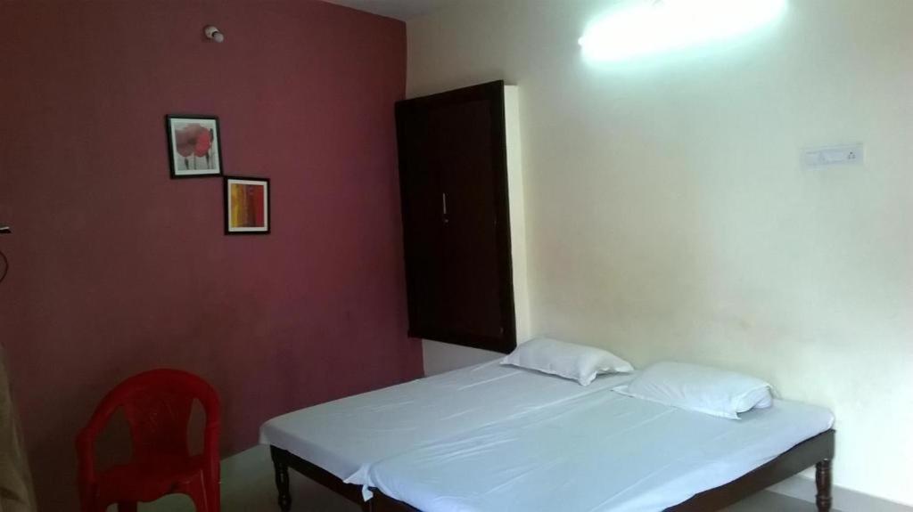 a small bedroom with a bed and a red wall at Xavier Guest House in Chennai