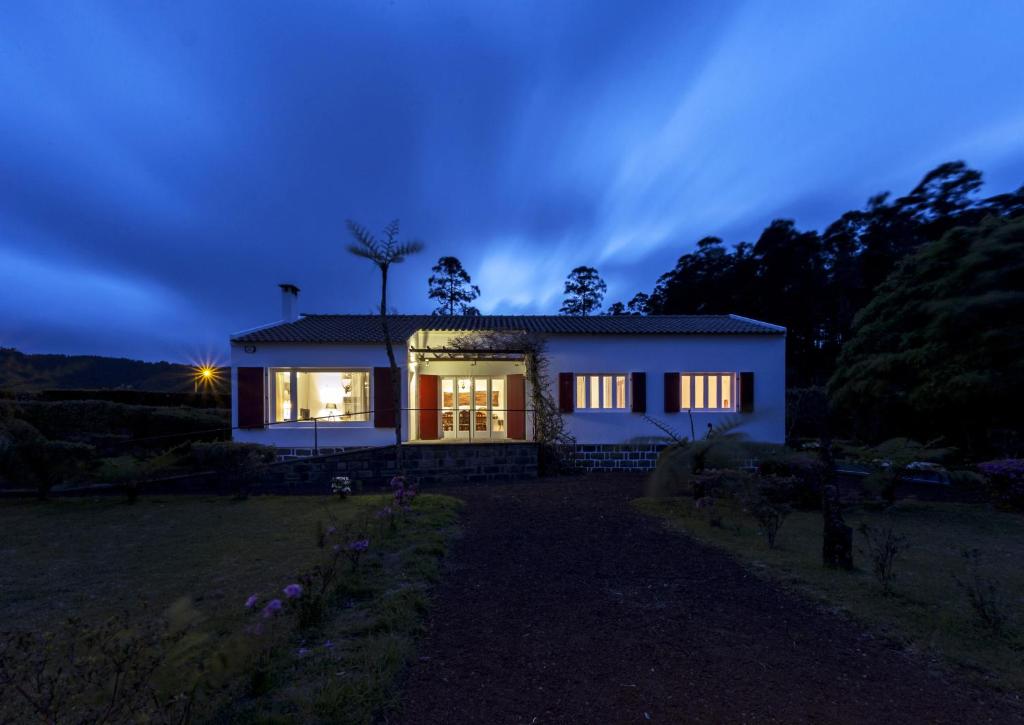 a small white house at night with the lights on at Lake View House in Sete Cidades