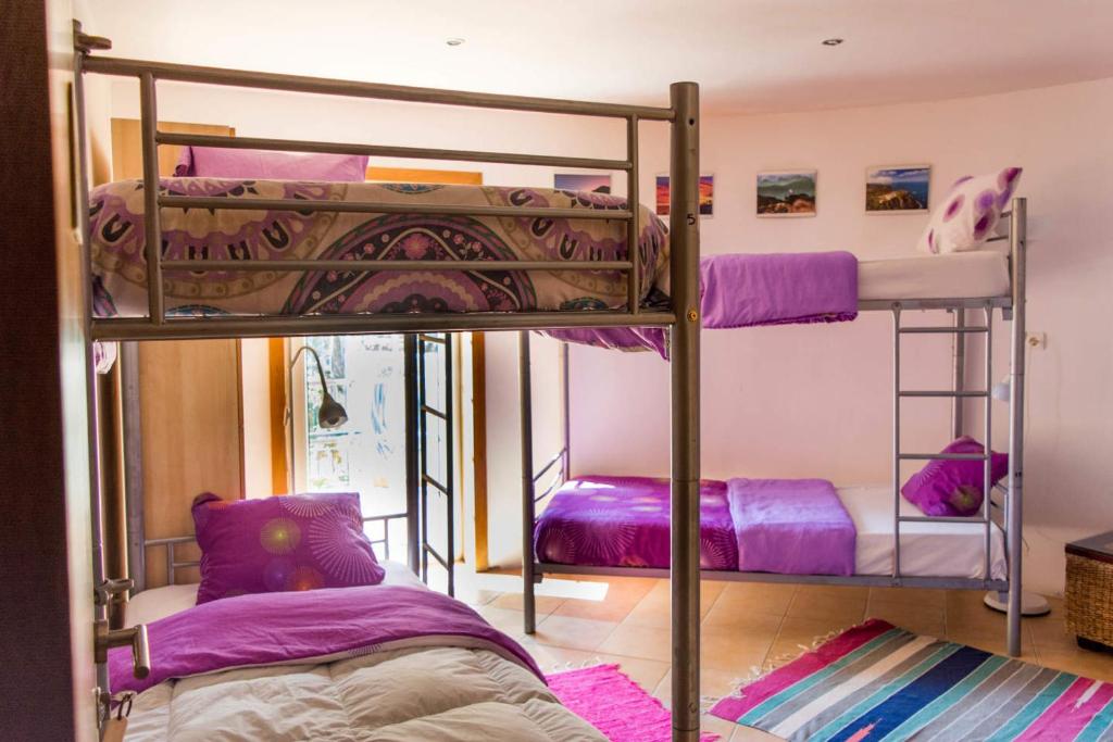 two bunk beds in a room with purple sheets at Amazigh Guincho Hostel & Suítes in Cascais