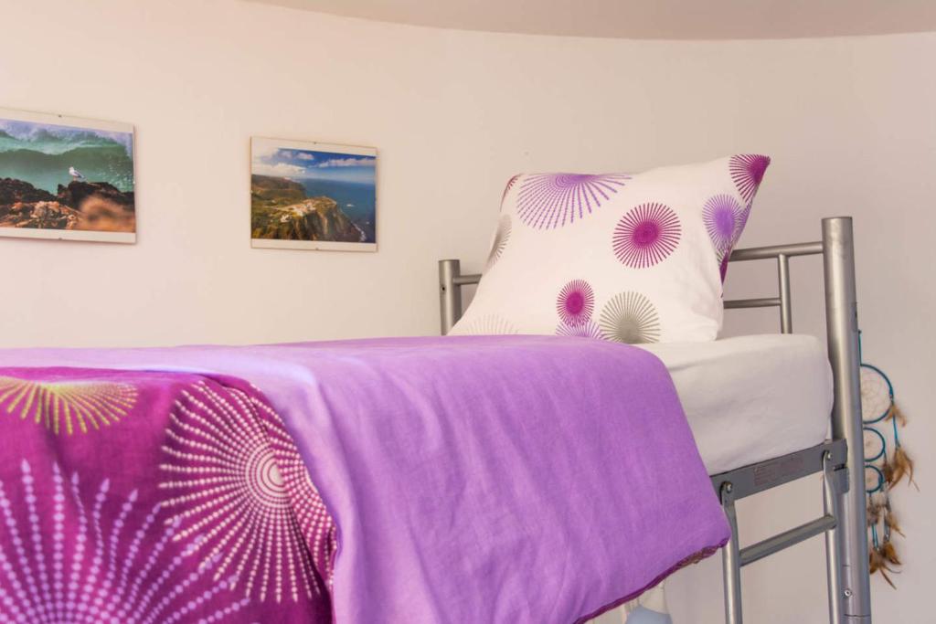 a bed with a purple blanket and a pillow at Amazigh Guincho Hostel & Suítes in Cascais