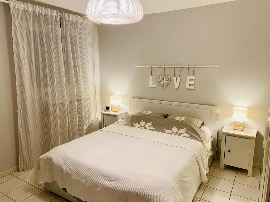 1 dormitorio con 1 cama blanca y 2 mesas con lámparas en Sweet Home - 55m2 appt, garden, swimming pool, parking, en Toulouse