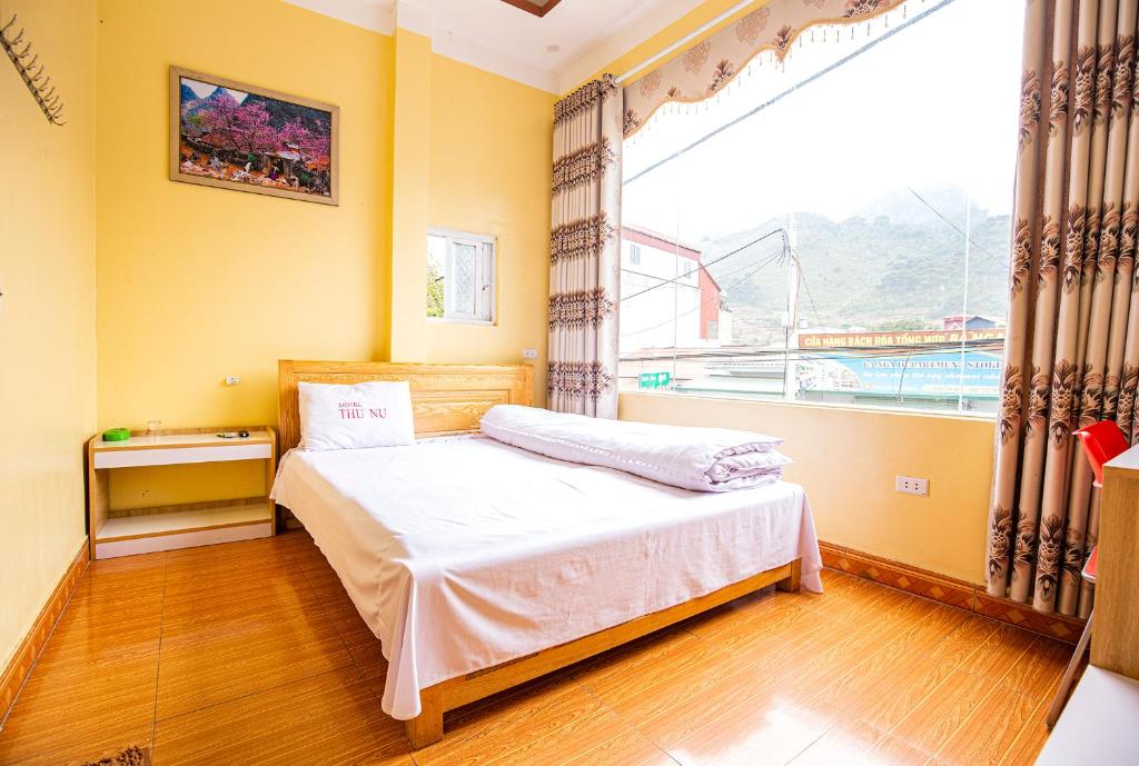 ein Schlafzimmer mit einem Bett und einem großen Fenster in der Unterkunft Nhà Nghỉ Thu Nụ in Mèo Vạc