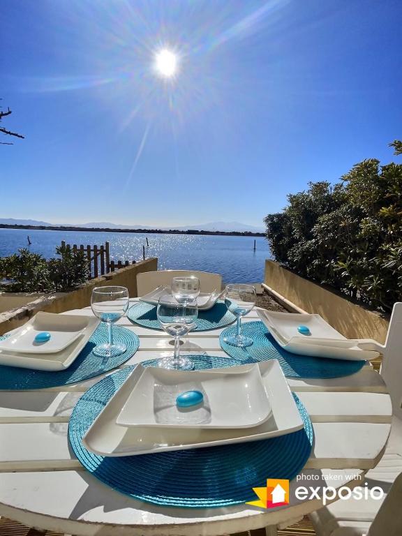 - une table avec des assiettes et des verres à vin dans l'établissement Les pieds dans l'eau, au Barcarès