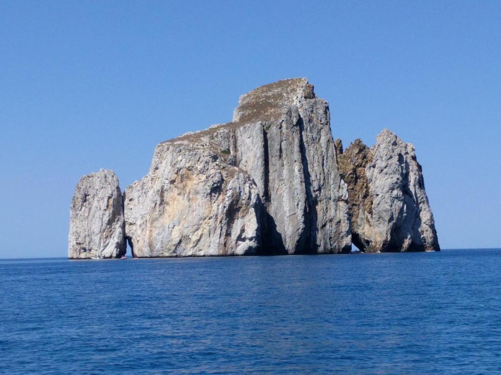 Une grande formation rocheuse dans l'océan par temps clair dans l'établissement Il Nido, à Gonnesa