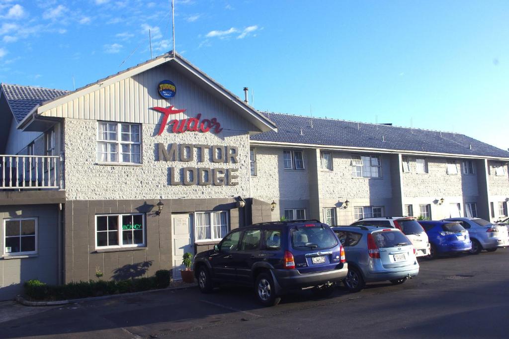 un hotel con coches estacionados en un estacionamiento en Tudor Motor Lodge, en Hamilton