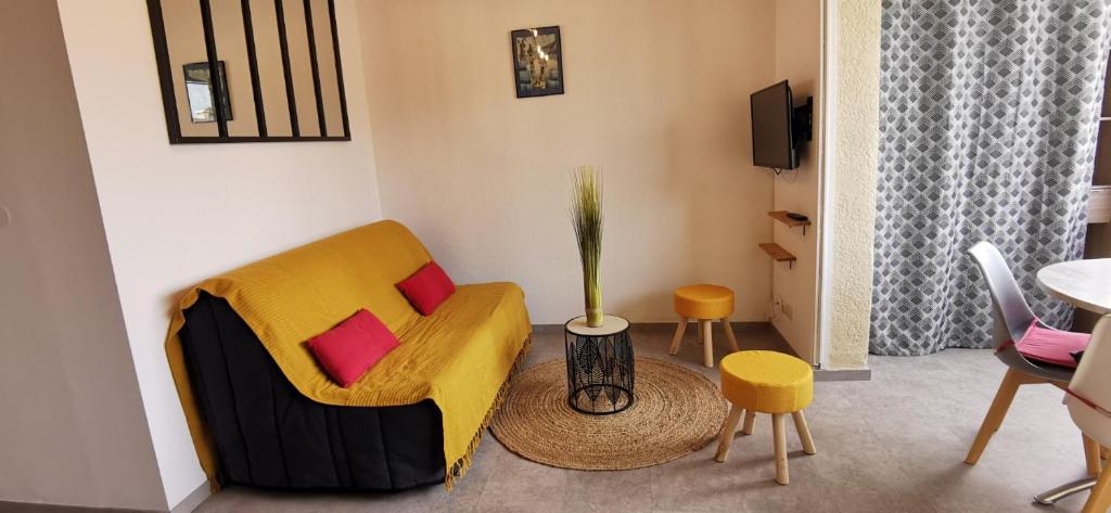 - un salon avec un canapé jaune et 2 oreillers rouges dans l'établissement Les éstivales Cap d'agde, au Cap d'Agde