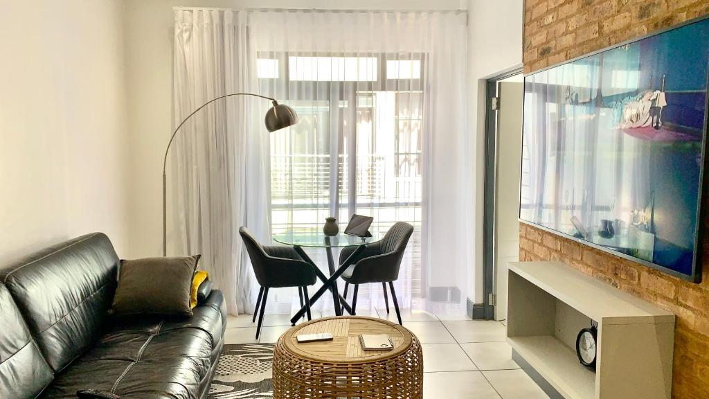 a living room with a couch and a table with chairs at CALDESMO - Upmarket Apartment in Pretoria