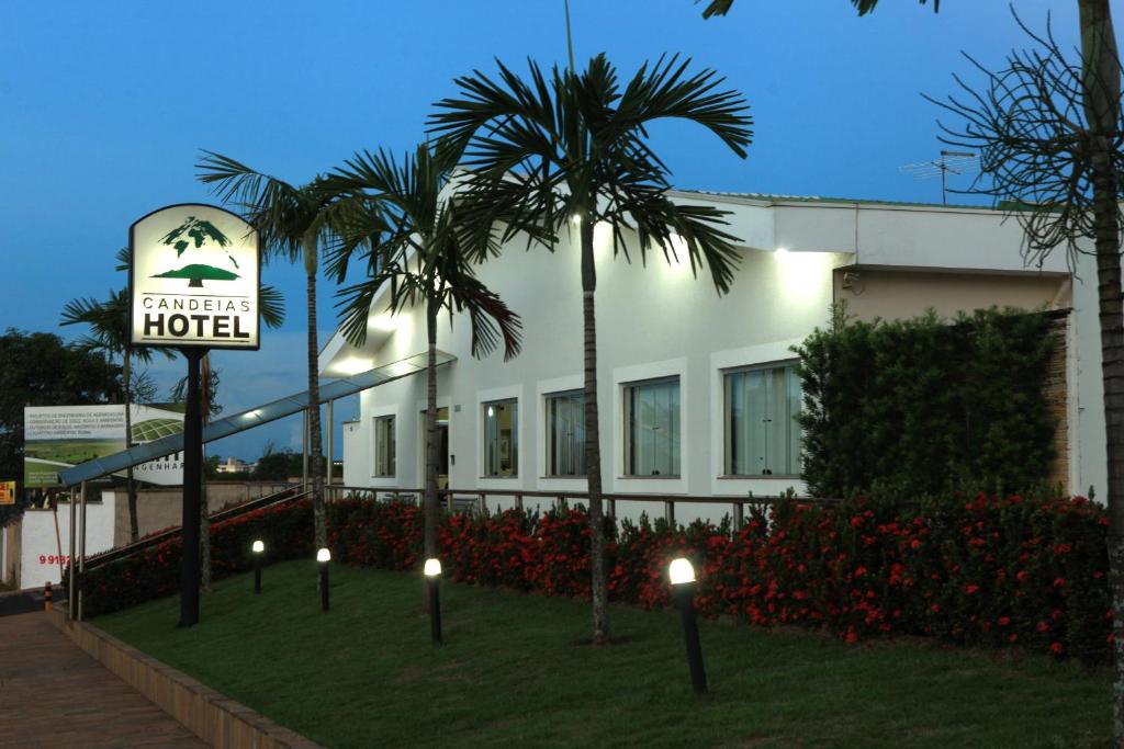 a hotel with palm trees in front of a building at Candeias Hotel in Batatais