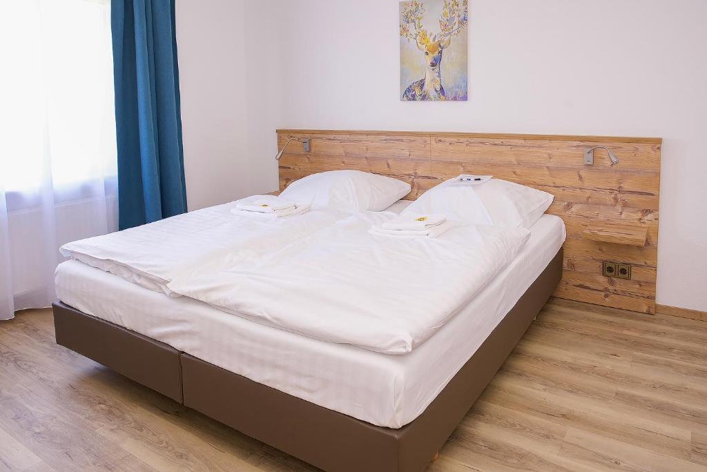 Cama en habitación con sábanas y almohadas blancas en Keller Höhe, en Andernach