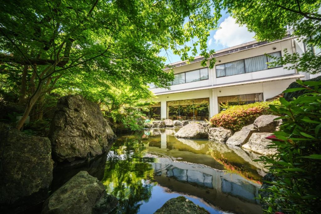 un jardín con un estanque frente a un edificio en Hotel Hoho "A hotel overlooking the Echigo Plain and the Yahiko mountain range" formerly Hotel Oohashi Yakata-no-Yu, en Niigata