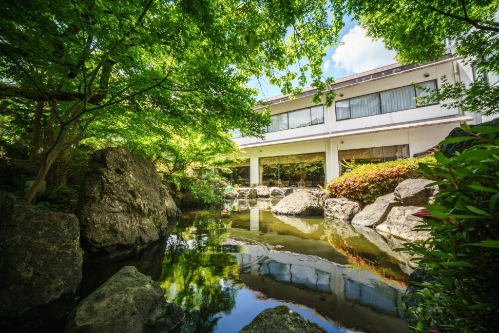 新瀉的住宿－Hotel Hoho "A hotel overlooking the Echigo Plain and the Yahiko mountain range" formerly Hotel Oohashi Yakata-no-Yu，一座花园,在一座建筑前设有一个池塘