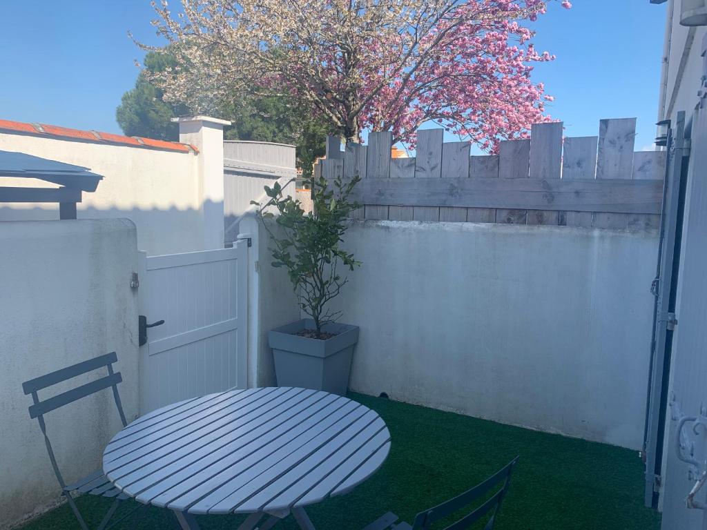 una valla blanca con una mesa y una maceta en Studio avec terrasse Saint Martin de Ré, en Saint-Martin-de-Ré