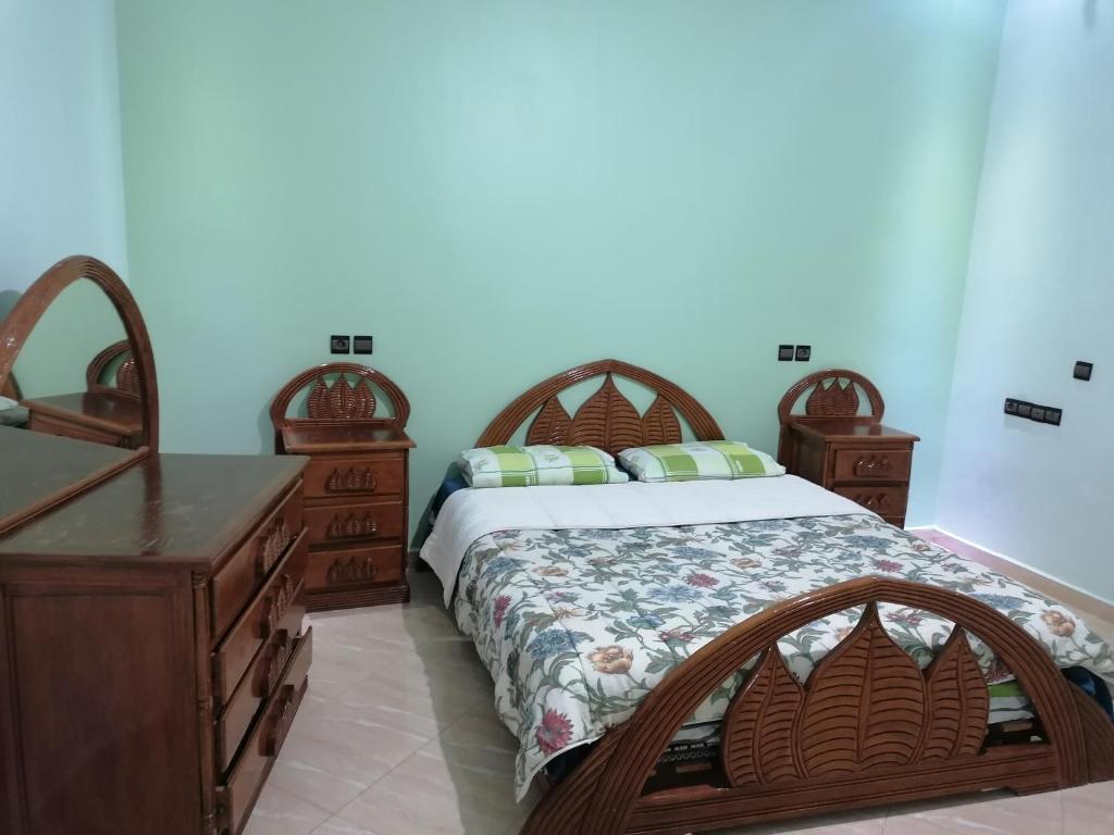 ein Schlafzimmer mit einem Bett und einer Holzkommode in der Unterkunft Appart el bassatine pr famille in Meknès
