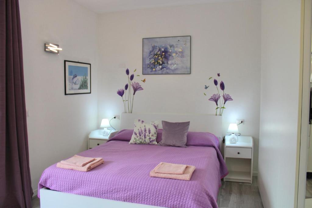 a bedroom with a purple bed with two towels on it at Appartamento “La casetta di Mirto” in Porlezza