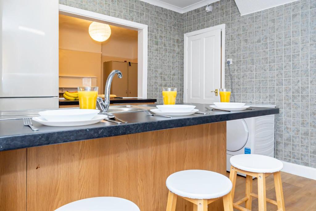 a kitchen with a counter with stools and a sink at Shirley House 4, Guest House, Self Catering, Self Check in with smart locks, use of Fully Equipped Kitchen, close to City Centre, Ideal for Longer Stays, Excellent Transport Links in Southampton