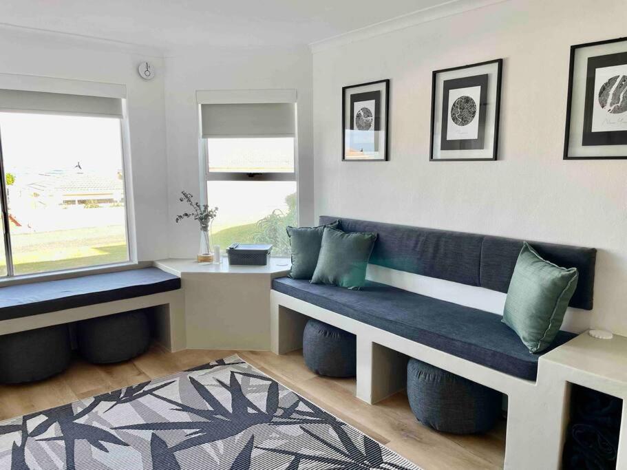 a living room with a blue bench and a window at Hermanus Sea Breeze in Hermanus