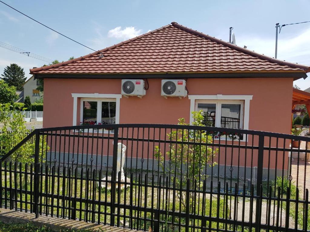 a pink house with a black fence at Rajmund vendeghaz in Balatonkeresztúr