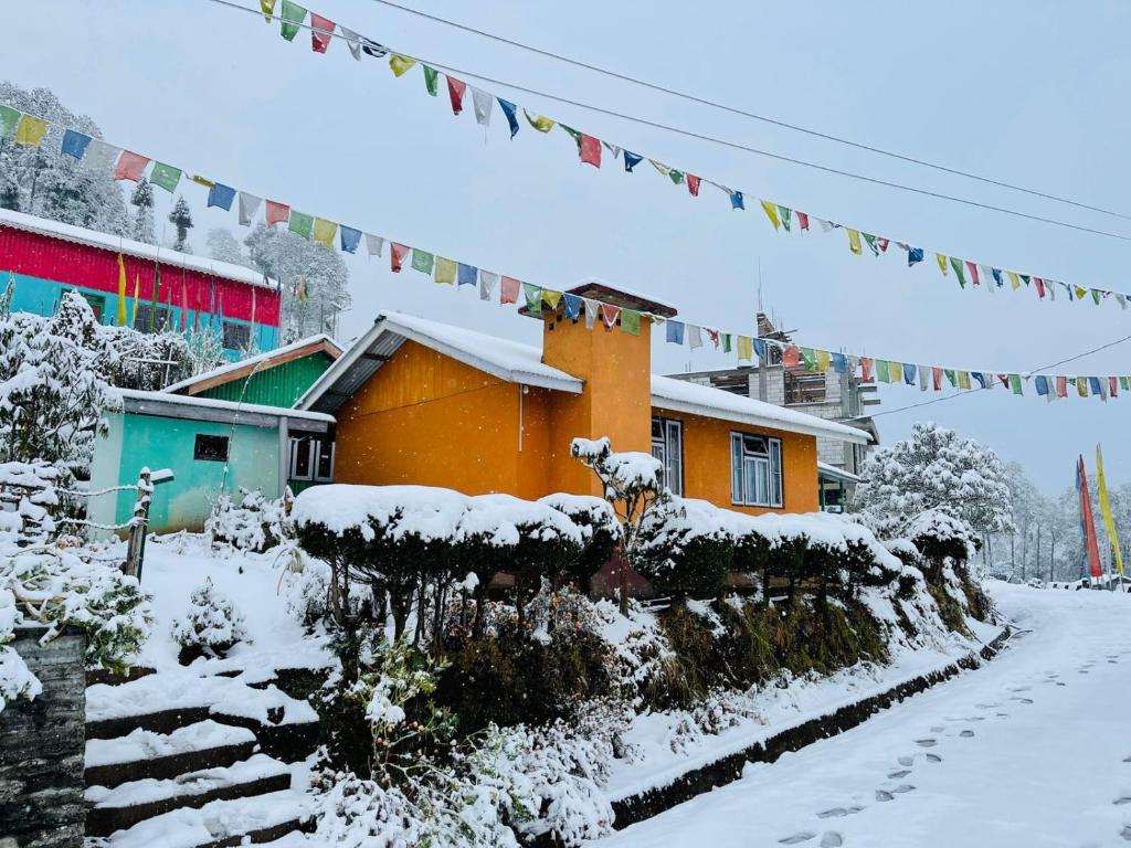 una casa cubierta de nieve frente a un edificio en Lali Gurash Homestay - Okhrey, en Sombāri