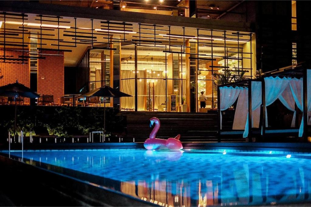 a pink swan in a pool in front of a building at Brique Suite in Chiang Mai