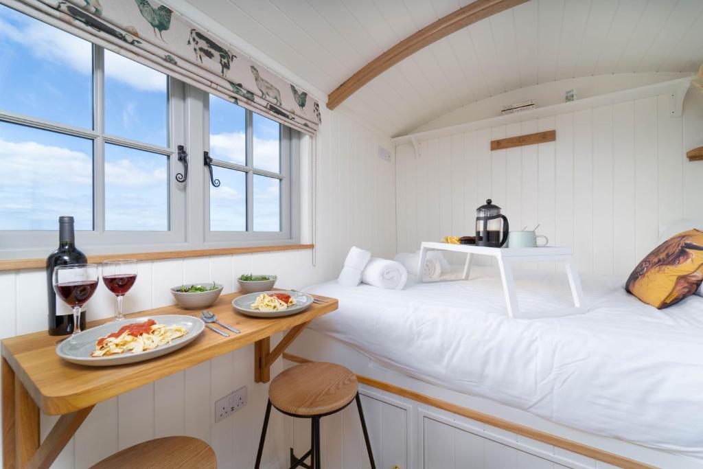 a room with a bed with two plates of food on it at The Shepherd's Hut in Penzance