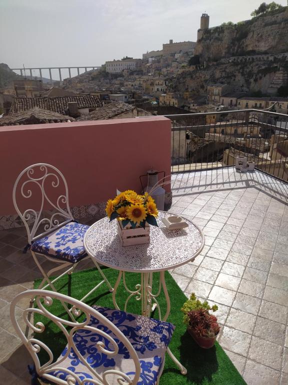 d'une table et de chaises fleuries sur le balcon. dans l'établissement Il terrazzo dei nonni, à Modica